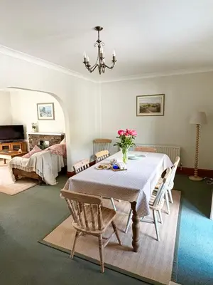a dining room with a table with a vase of flowers on it at Kionslieu Farm Cottages in Foxdale