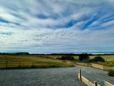a dirt road in a field with a fence at Firth View 1 - Luxury Cottage with Sea View & Hot Tub, Ayr in Ayr