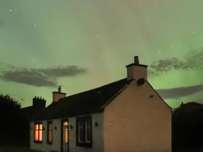 a house with a green sky in the background at Kilquhanity Cottage in Castle Douglas