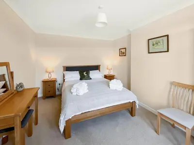 a bedroom with a bed with a desk and a chair at Kilquhanity Cottage in Castle Douglas