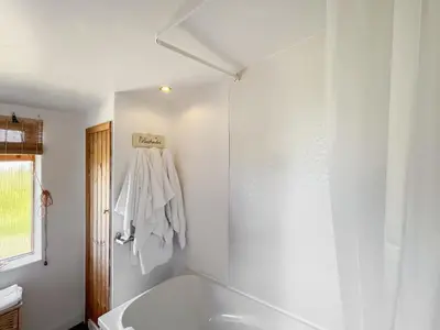 a white bathroom with a tub and a window at Rose Cottage in Port Logan