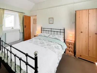 a bedroom with a large bed and a window at Rose Cottage in Port Logan