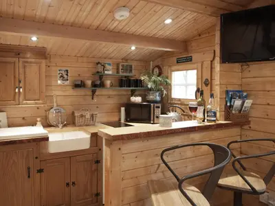 a kitchen with wooden cabinets and a counter with two chairs at The Signal Box in Girvan