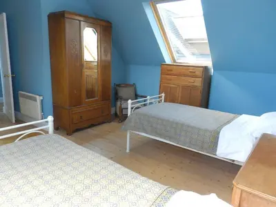 a bedroom with two beds and a dresser and a window at Castleside Croft in Kildonan