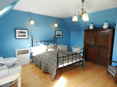 a bedroom with a bed with blue walls at Castleside Croft in Kildonan