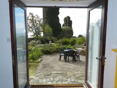 an open door to a patio with a table and chairs at Castleside Croft in Kildonan
