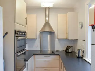 a kitchen with white cabinets and a stove at Ardbeag in Whiting Bay