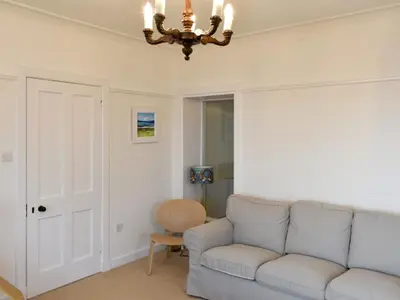 a living room with a couch and a chandelier at Ardbeag in Whiting Bay