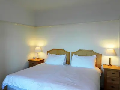a bedroom with two beds with white sheets and two lamps at Ardbeag in Whiting Bay