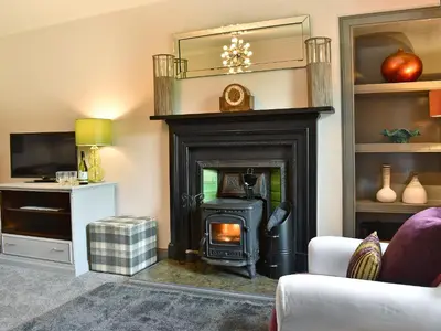 a living room with a fireplace and a mirror at 2 Northbank Cottages in Whiting Bay