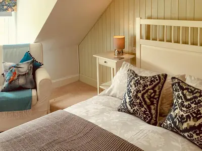 a bedroom with a bed with pillows and a chair at 2 Northbank Cottages in Whiting Bay