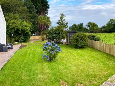 a yard with blue flowers in the grass at 2 Northbank Cottages in Whiting Bay