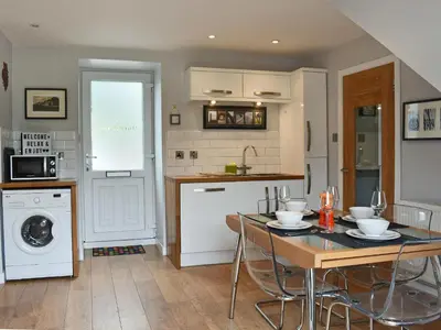 a kitchen with a table and chairs and a kitchen with a washing machine at 2 Northbank Cottages in Whiting Bay