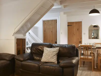 a living room with a leather couch and a table at Ivy Cottage in Whiting Bay
