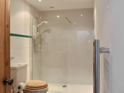a bathroom with a toilet and a glass shower at Ivy Cottage in Whiting Bay