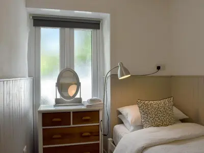 a bedroom with a bed and a mirror on a dresser at Ivy Cottage in Whiting Bay
