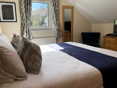 a bedroom with a large bed with a window at Oakvale - Oak Leaf in Braithwaite