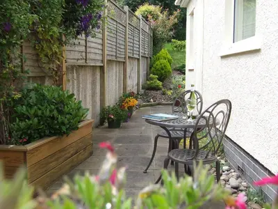 a patio with two chairs and a table and flowers at Oakvale - Oak Leaf in Braithwaite