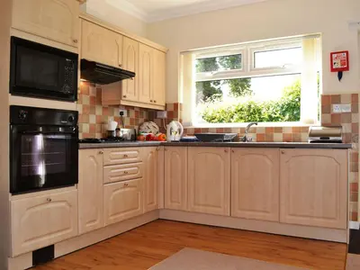 a kitchen with wooden cabinets and a window at Oakvale - Oak Leaf in Braithwaite