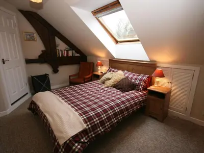 a attic bedroom with a bed and a window at Rowan Cottage in Borgue