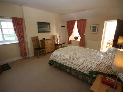a bedroom with a bed and two windows at East Cottage in Mainsriddle