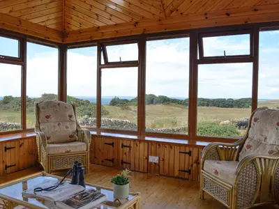a room with two chairs and a table and windows at Allanhead in Borgue