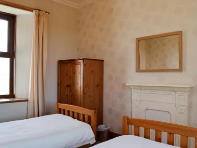 a bedroom with two beds and a wooden cabinet at Allanhead in Borgue