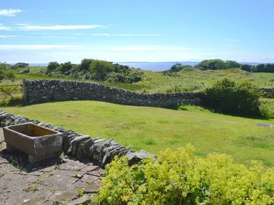 a stone wall in a field with a grassy field at Allanhead in Borgue