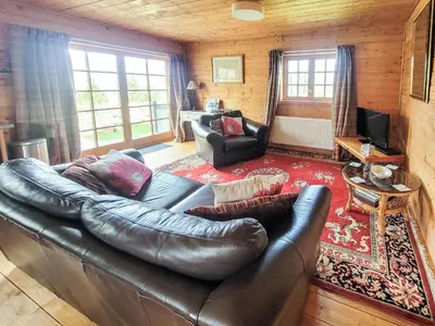 a living room with a leather couch and a television at Forest Lodge in Dumfries