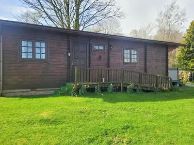 a log cabin with a porch and a house at Forest Lodge in Dumfries