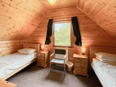 a bedroom with two beds and a window in a log cabin at Criffel Lodge in Ringford