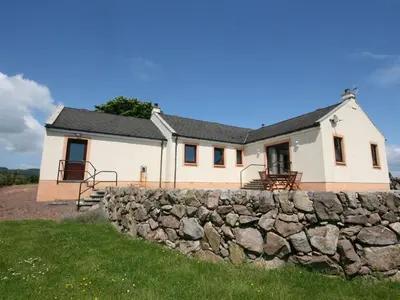 a white house with a stone wall at Rocky Knowe in Dalbeattie