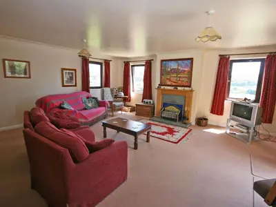 a living room with red furniture and a fireplace at Rocky Knowe in Dalbeattie