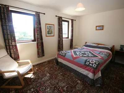 a bedroom with a bed and a chair and a window at Rocky Knowe in Dalbeattie