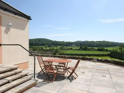 a table and chairs on a patio with a view at Rocky Knowe in Dalbeattie