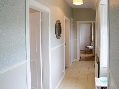 a hallway with white doors and a tile floor at Palmallet Cottage in Whithorn