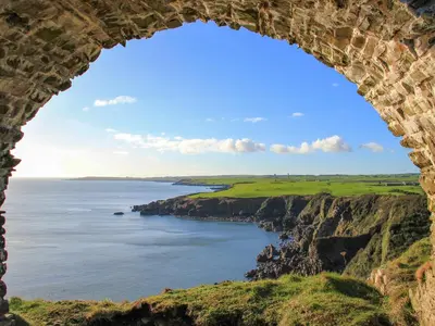 a view of the ocean through a stone archway at Palmallet Cottage in Whithorn