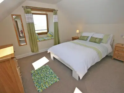a bedroom with a bed and a window and a mirror at Cairndoon Steading Whithorn in Carleton