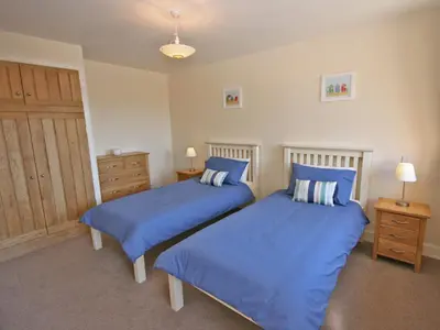 two beds in a bedroom with blue sheets at Cairndoon Steading Whithorn in Carleton