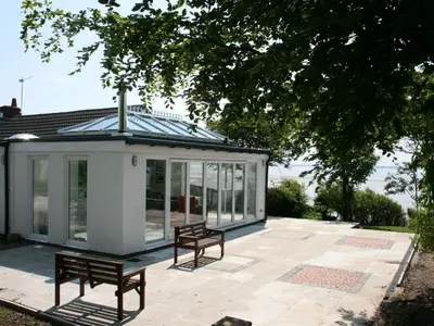 a conservatory with two benches on a patio at Dornock Brow Cottage in Dornock