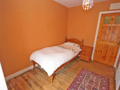 a small bedroom with a bed and a wooden floor at Dornock Brow Cottage in Dornock