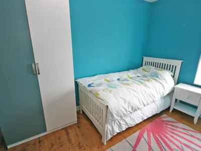 a small bedroom with a bed with a blue wall at Dornock Brow Cottage in Dornock