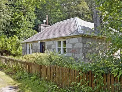 an old stone house behind a wooden fence at Squirrel Cottage in Palnure