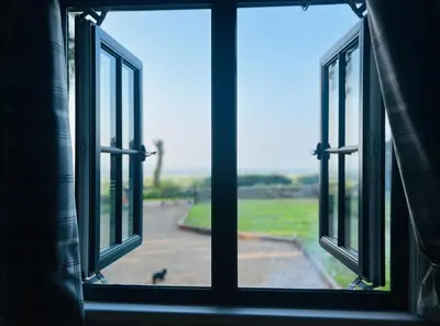 an open window with a view of a field at Herdie Hideaway - Shepherds Hut in Wigton