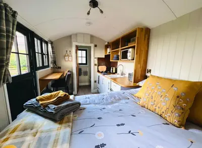 a bedroom with a large bed in a small room at Herdie Hideaway - Shepherds Hut in Wigton