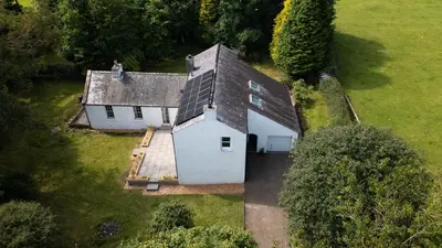 an overhead view of a white house with solar panels on it at Large country house with garden, outdoor spa area & games room with Hot Tub and Fire Pit in Wigtown