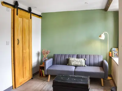 a living room with a blue couch and a green wall at Pickles Barn in Ireby