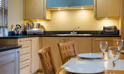 a kitchen with a table and chairs with wine glasses at Underscar - Littledale in Keswick