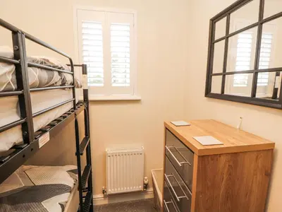 a room with bunk beds and a desk and a window at Squirrel Cottage in Penrith