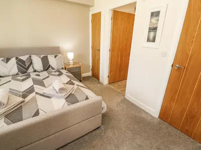 a bedroom with a bed and a couch and a door at Squirrel Cottage in Penrith